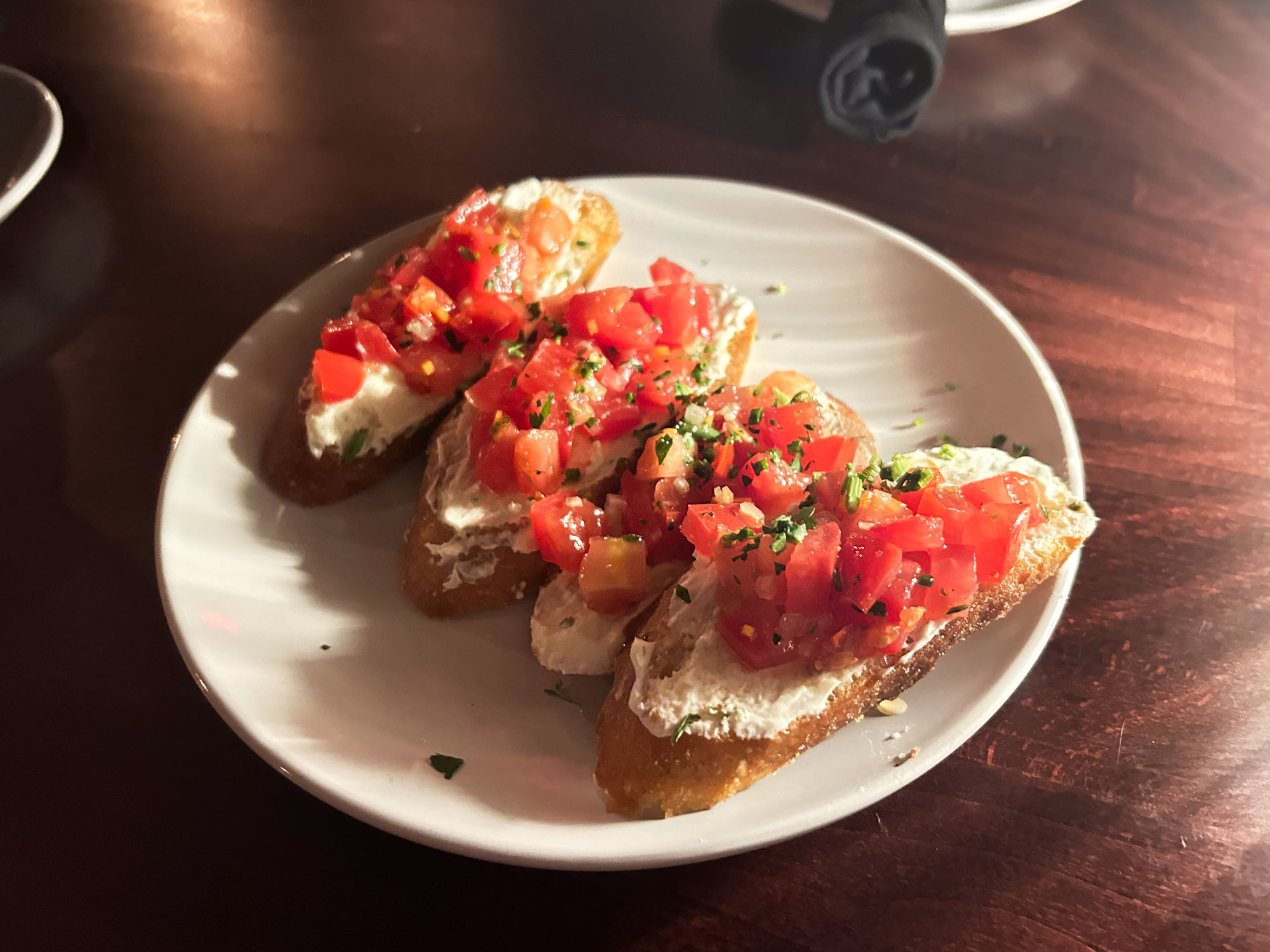 bruschetta on a white plate and brown table